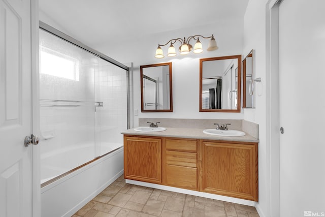 bathroom with double vanity, stone finish flooring, shower / bath combination with glass door, and a sink