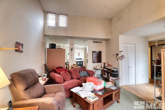 carpeted living room featuring visible vents and a high ceiling