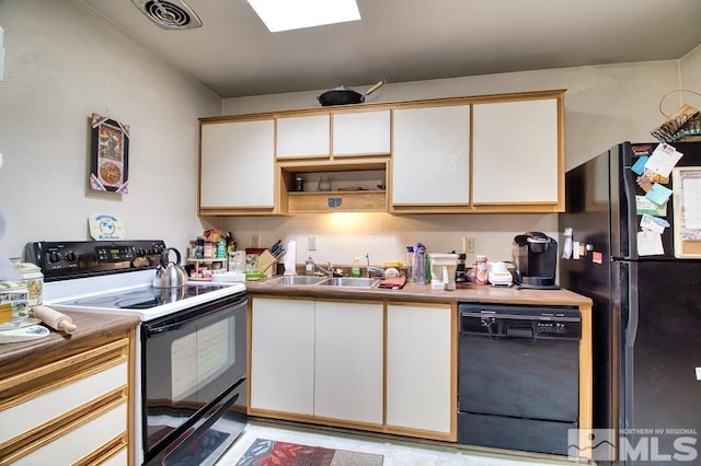 kitchen featuring visible vents, white cabinets, black appliances, and a sink