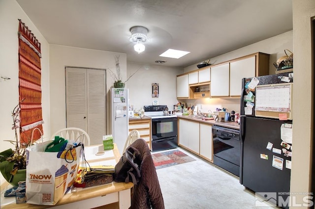 kitchen with a sink, black appliances, light countertops, and white cabinetry