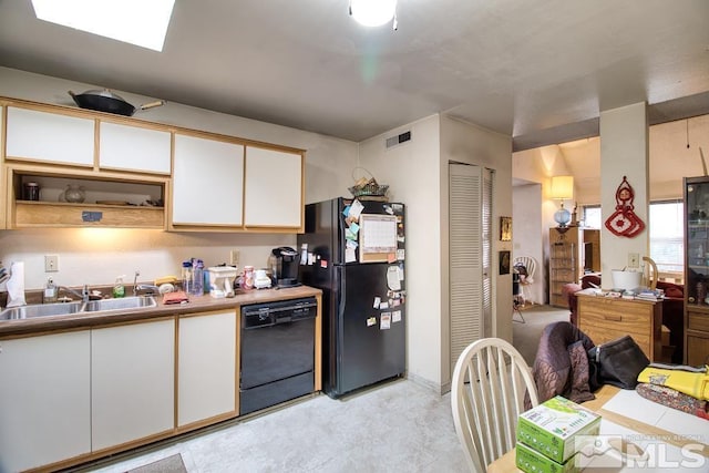 kitchen featuring visible vents, a sink, black appliances, white cabinets, and open floor plan