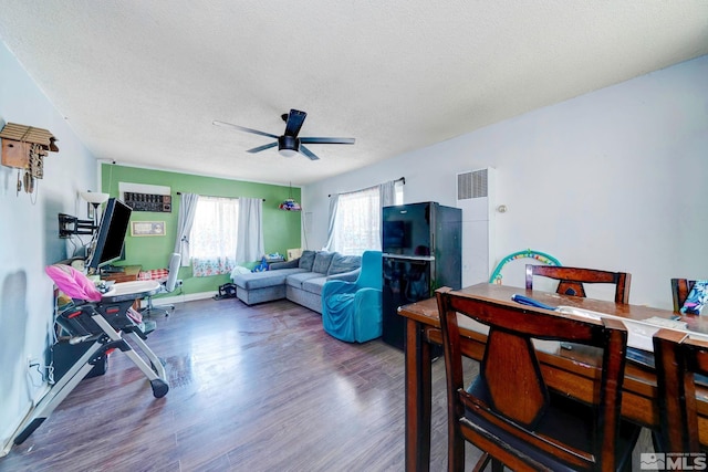 living room featuring baseboards, a textured ceiling, wood finished floors, and a ceiling fan