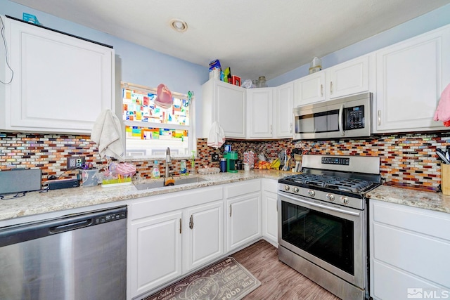 kitchen featuring tasteful backsplash, white cabinetry, stainless steel appliances, and a sink