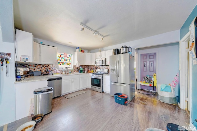 kitchen featuring backsplash, stainless steel appliances, light wood-style floors, white cabinets, and light countertops