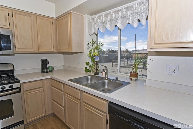 kitchen featuring light brown cabinetry, appliances with stainless steel finishes, and a sink