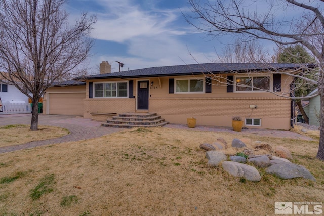 ranch-style home featuring fence, a front yard, a garage, brick siding, and a chimney