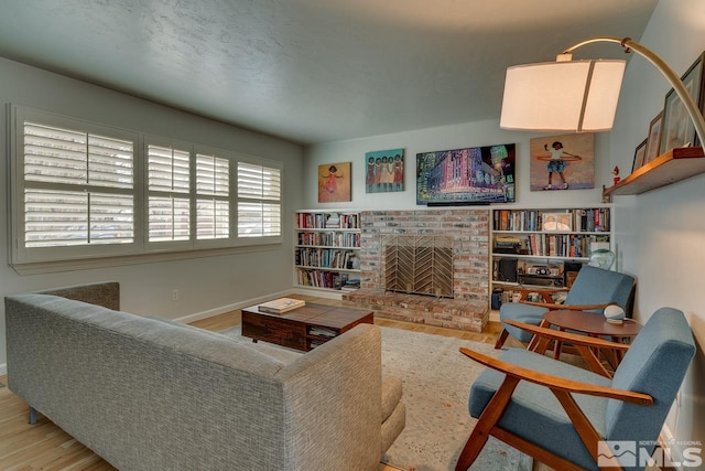 living area with a fireplace, baseboards, and wood finished floors