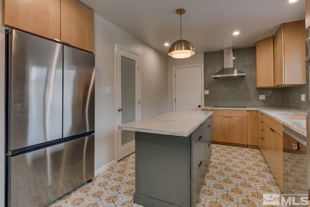 kitchen featuring decorative backsplash, wall chimney range hood, freestanding refrigerator, and a kitchen island