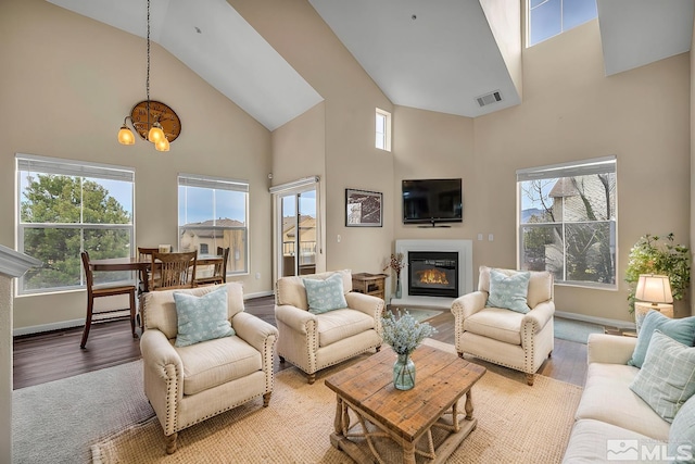 living area featuring a wealth of natural light, a glass covered fireplace, and light wood finished floors