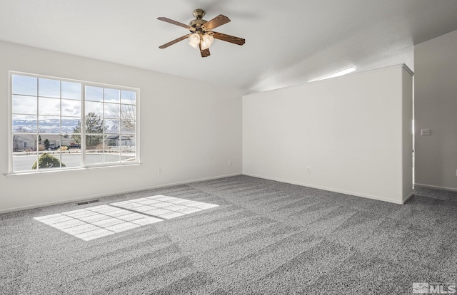 spare room with visible vents, baseboards, ceiling fan, vaulted ceiling, and carpet flooring