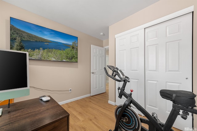 workout room featuring baseboards and light wood-style floors