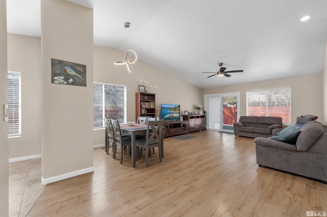 dining room featuring baseboards, lofted ceiling, a ceiling fan, and light wood finished floors