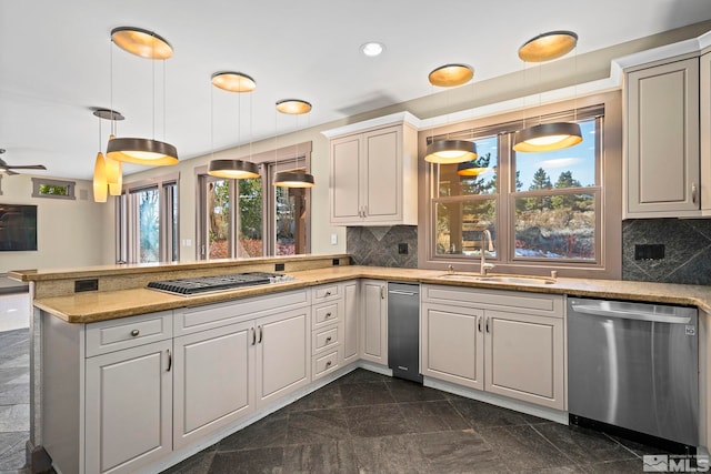 kitchen featuring a sink, backsplash, appliances with stainless steel finishes, and a peninsula