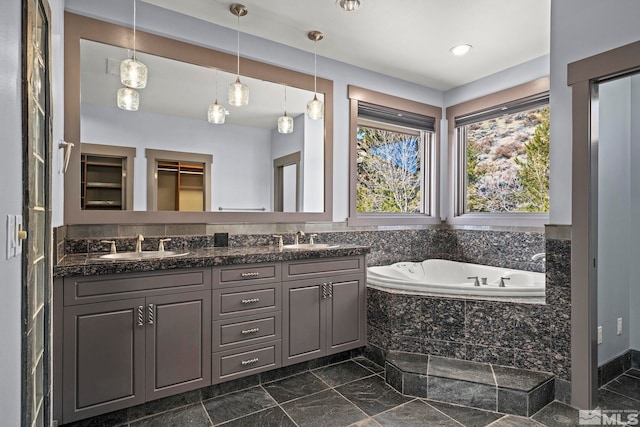 full bath featuring a garden tub, a spacious closet, double vanity, and a sink