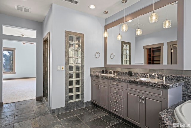 bathroom with a sink, visible vents, a bathing tub, and double vanity