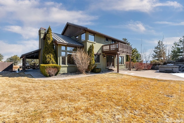 back of house with a standing seam roof, a hot tub, a yard, metal roof, and a patio area