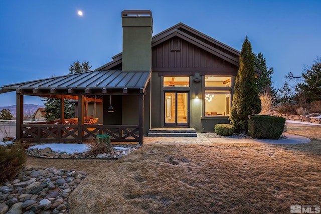 back of property featuring metal roof, board and batten siding, a chimney, and a standing seam roof