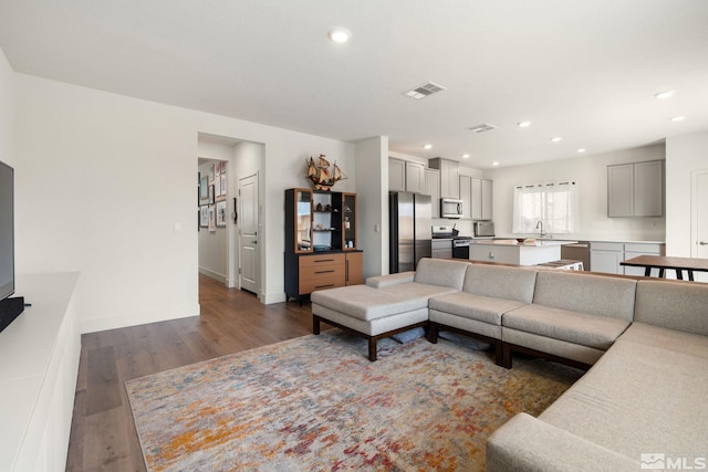 living room featuring recessed lighting, dark wood-style floors, visible vents, and baseboards