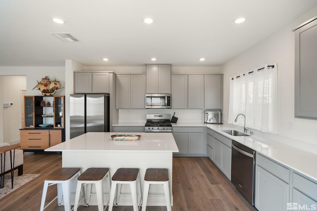 kitchen with visible vents, a breakfast bar, gray cabinets, a sink, and stainless steel appliances