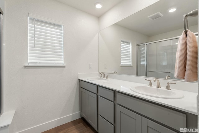 bathroom with a sink, visible vents, wood finished floors, and a stall shower