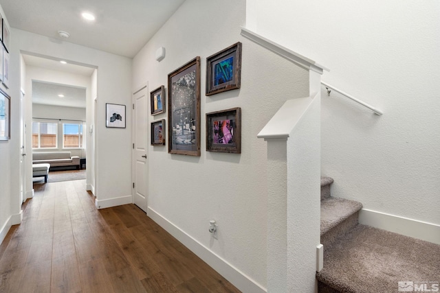 hallway featuring stairs, dark wood-type flooring, recessed lighting, and baseboards