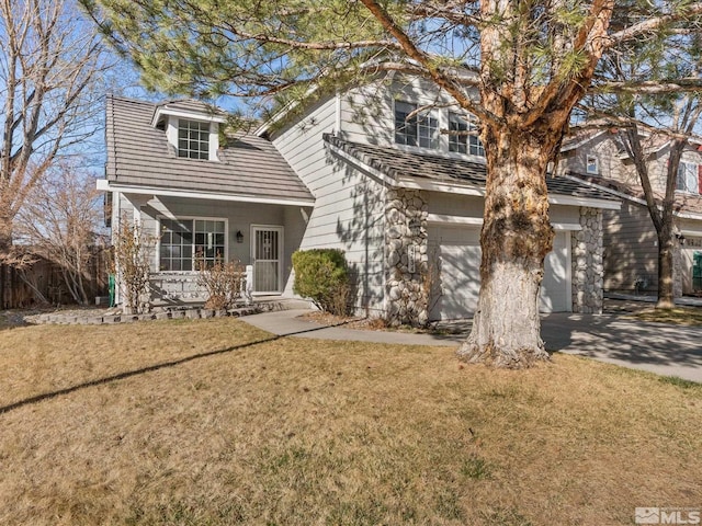traditional home featuring a front yard, a porch, an attached garage, and aphalt driveway