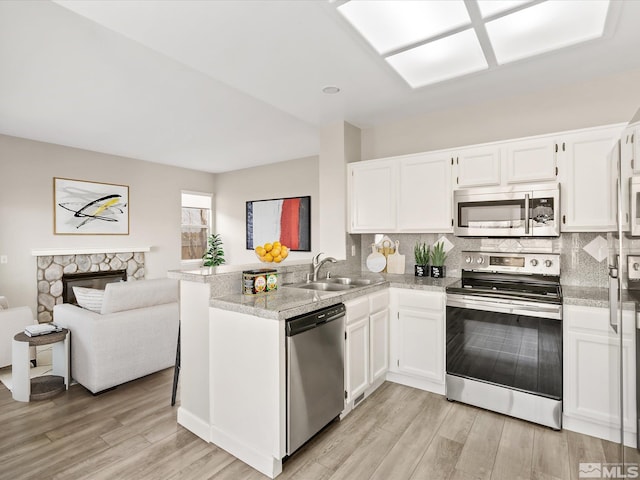 kitchen with a sink, a peninsula, white cabinetry, and stainless steel appliances