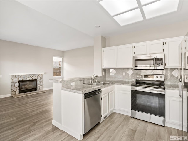 kitchen with a sink, stainless steel appliances, backsplash, and white cabinets