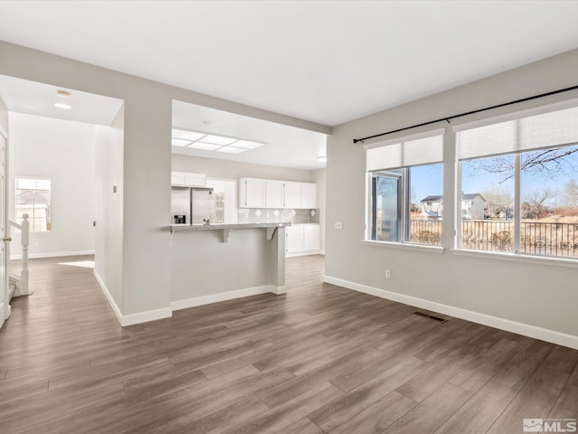 unfurnished living room featuring wood finished floors, visible vents, and baseboards