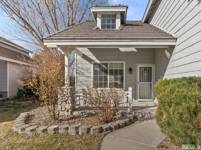 entrance to property featuring covered porch and a tile roof