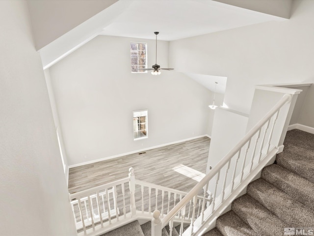 stairway featuring vaulted ceiling, baseboards, a ceiling fan, and wood finished floors