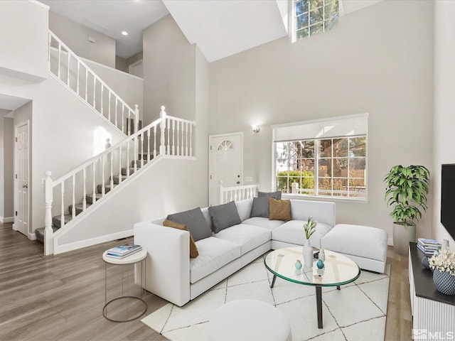 living area with baseboards, stairway, recessed lighting, a high ceiling, and wood finished floors