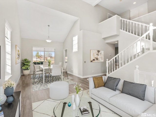 living room with stairway, wood finished floors, baseboards, and high vaulted ceiling