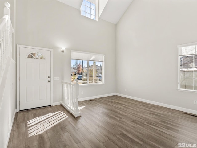 entryway featuring visible vents, a healthy amount of sunlight, high vaulted ceiling, and wood finished floors