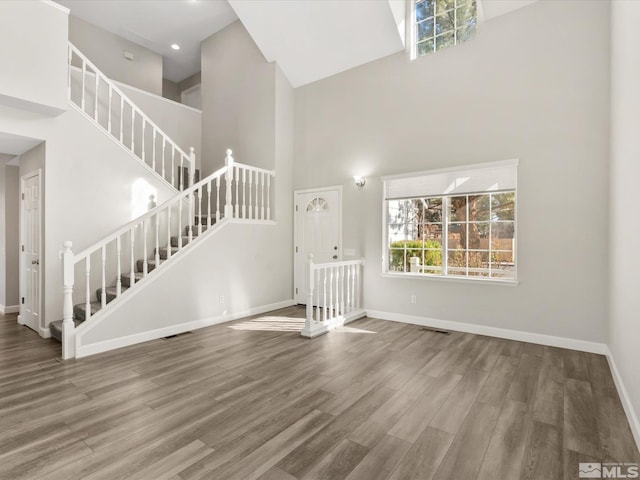 interior space with a high ceiling, stairway, wood finished floors, and baseboards