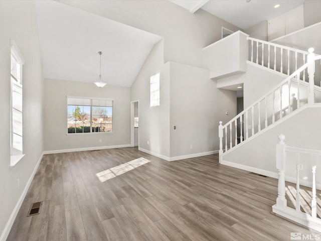 entryway featuring stairs, wood finished floors, visible vents, and high vaulted ceiling