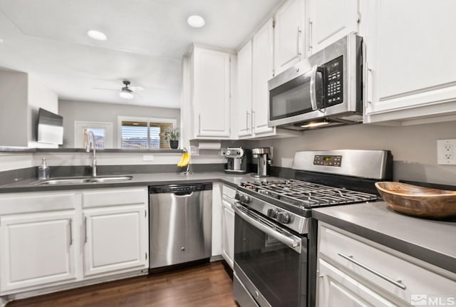 kitchen featuring ceiling fan, a sink, white cabinets, appliances with stainless steel finishes, and dark countertops