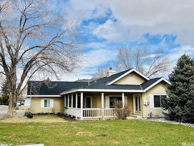 view of front of property with a shingled roof, a front yard, and a chimney