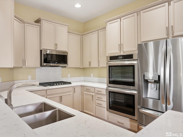 kitchen with a sink, stainless steel appliances, light stone counters, and recessed lighting