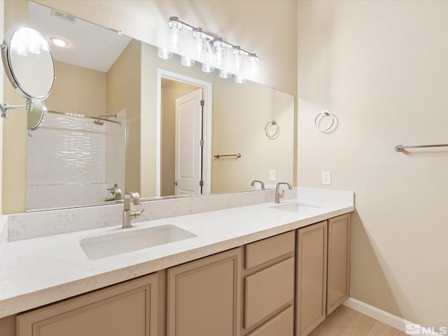 bathroom featuring double vanity, a shower, visible vents, and a sink