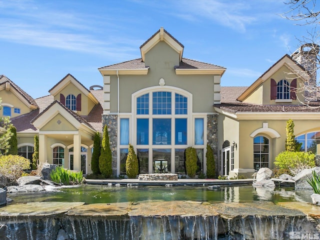 rear view of property featuring stone siding and stucco siding