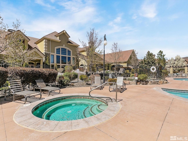 pool with a patio, a community hot tub, and fence