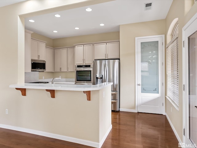 kitchen with a breakfast bar, a peninsula, visible vents, and stainless steel appliances