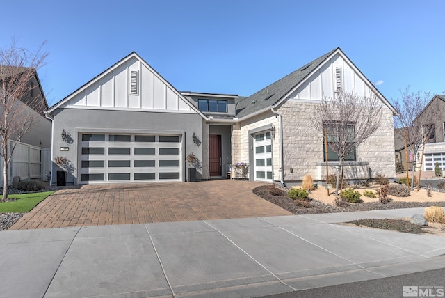 view of front of house featuring stone siding, board and batten siding, decorative driveway, and a garage