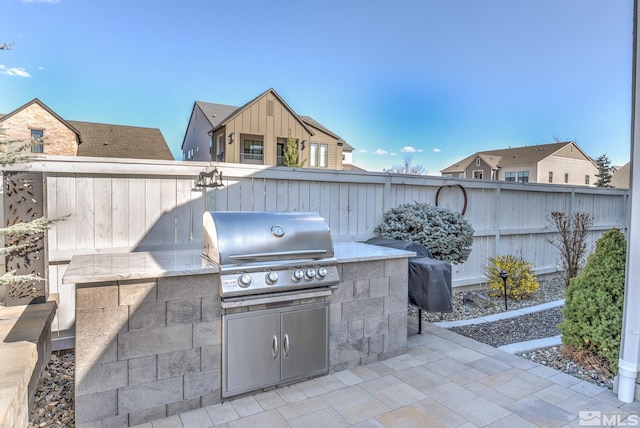 view of patio featuring exterior kitchen, area for grilling, and fence