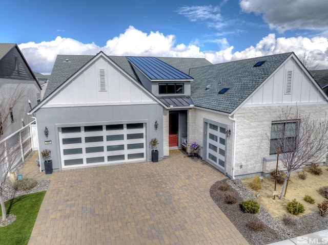 view of front of property featuring a standing seam roof, a garage, decorative driveway, board and batten siding, and metal roof