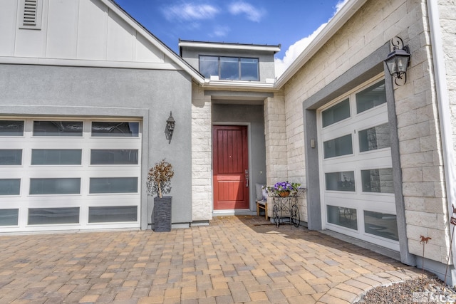 doorway to property featuring an attached garage and stucco siding