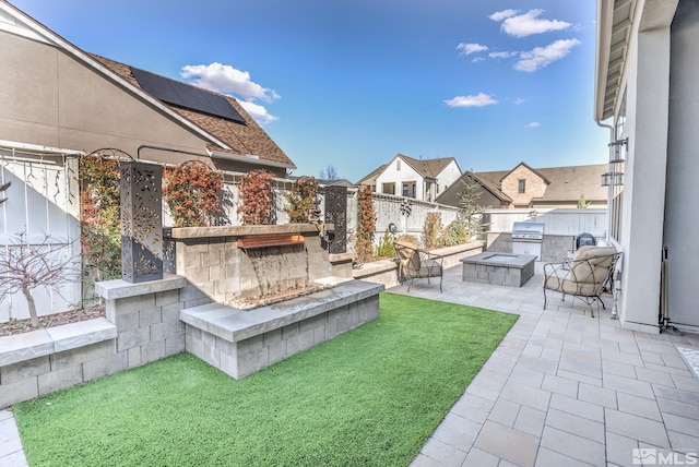 view of yard with area for grilling, an outdoor stone fireplace, a fenced backyard, and a patio area