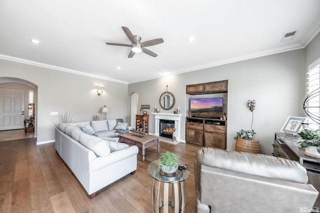 living area with arched walkways, visible vents, ceiling fan, and wood finished floors