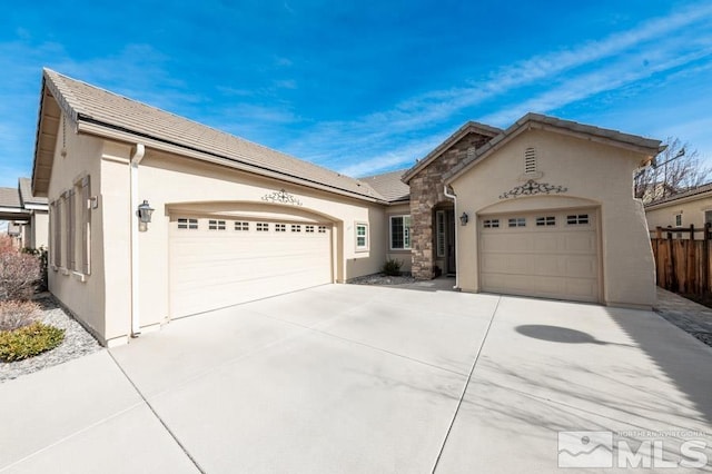 view of front of house featuring fence, a tile roof, stucco siding, driveway, and an attached garage